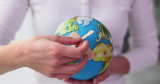 Donna che tiene il globo del pianeta Terra con intonaco adesivo. Pandemia e vaccinazione nel mondo - Filmati, video