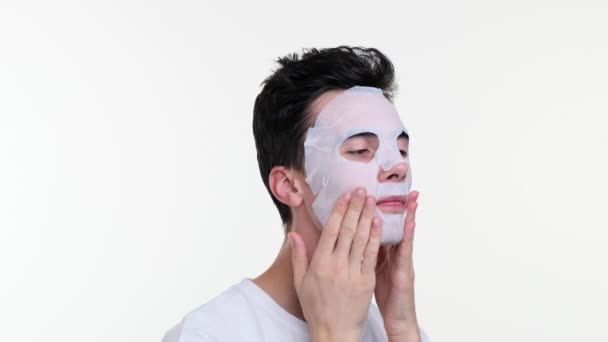 De man brengt sierlijk een gezichtsmasker aan, gezicht reflecteert rust en focus. De gladde textuur van het masker glijdt op de huid, omhult hem in een moment van verjonging en zelfverzorging. - Video