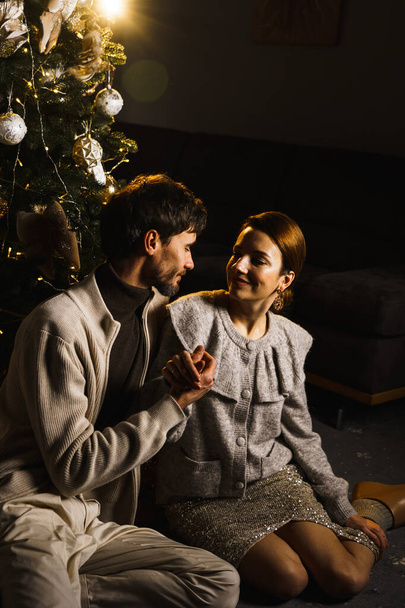 Ευτυχισμένος οικογενειακός πατέρας, μητέρα και γιος στολίζουν το δέντρο της Πρωτοχρονιάς, διασκεδάζουν, χορεύουν και ξεπακετάρουν δώρα. Η ιδέα των Χριστουγέννων και της Πρωτοχρονιάς. Κάθετη βολή - Φωτογραφία, εικόνα