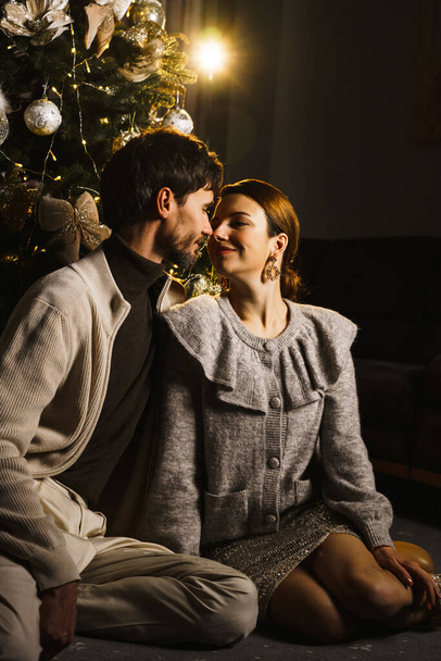 Щасливі сім'ї батько, мати і син прикрашають новорічну ялинку, розважаються, танцюють і розпаковують подарунки. Концепція Різдва та Нового року. Вертикальний постріл - Фото, зображення