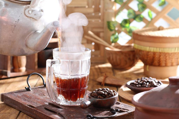 гарячий чай з чайником і чашкою чаю на дерев'яному столі на фоні - Фото, зображення