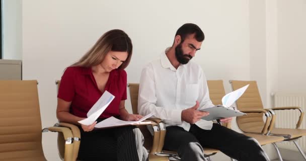 Ділова жінка і чоловік готуються до переговорів з інвесторами і читають документи в очікуванні зустрічі в офісному лобі. Підготовка до співбесіди в компанії та бізнес-лобі - Кадри, відео
