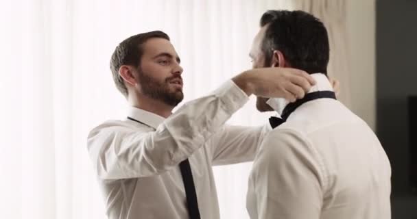 Wedding, dressing and friend helping groom with fashion in a bedroom. Best man, care and style or clothing with people happy for marriage or commitment ceremony with love and bonding for affection. - Footage, Video