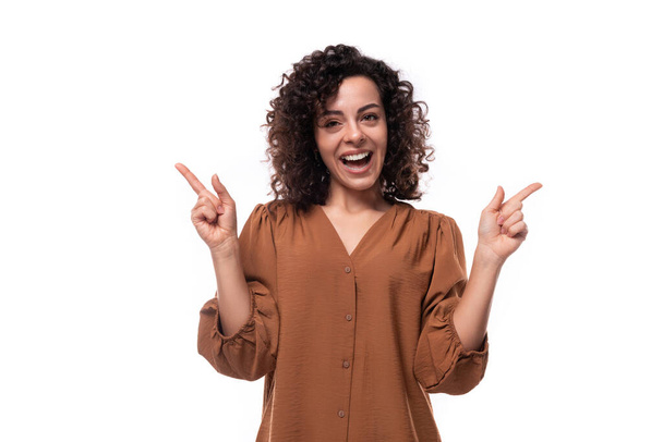 jovem mulher de negócios encaracolado alegre vestida com uma camisa marrom em um fundo branco. - Foto, Imagem