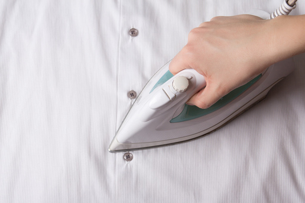 close up of female hand with iron ironing shirt - Photo, Image