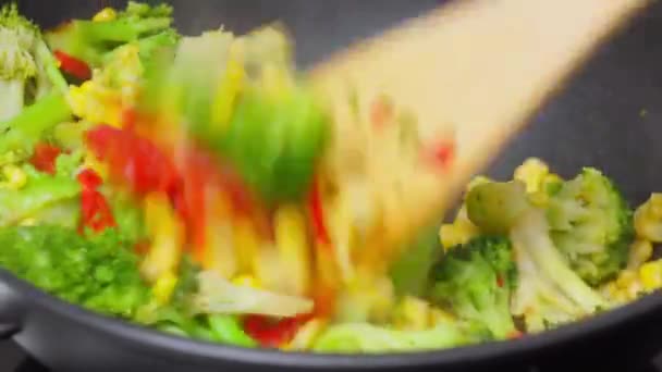 Sartén llena de verduras y una cuchara de madera. Cocinar en una sartén wok - Metraje, vídeo