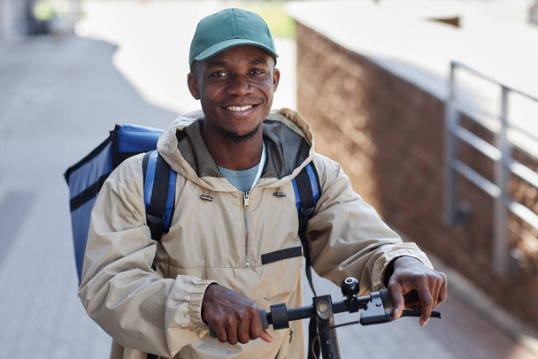 街の食糧配達労働者としての黒人の微笑みの肖像 - 写真・画像