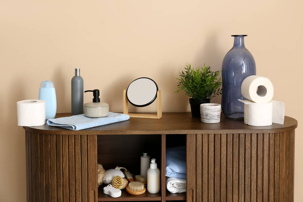 Gabinete de madera con diferentes suministros de baño y cosméticos cerca de la pared de color - Foto, Imagen