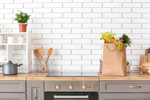 Saco de papel com diferentes produtos e utensílios no balcão na cozinha - Foto, Imagem