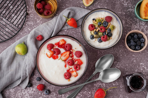 Bowls of tasty semolina porridge with fresh berries on grey background - Photo, Image