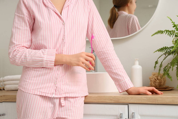 Nainen hammasharjalla kylpyhuoneessa
 - Valokuva, kuva