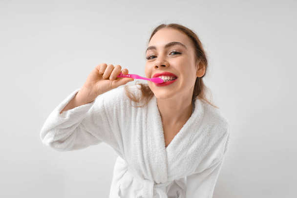 Bella giovane donna lavarsi i denti su sfondo bianco - Foto, immagini