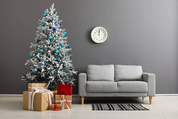 灰色の壁の近くのギフト用の箱そしてソファーが付いている美しいクリスマス ツリー - 写真・画像