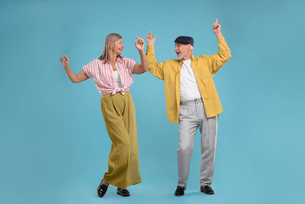 Senior couple dancing together on light blue background - Foto, afbeelding
