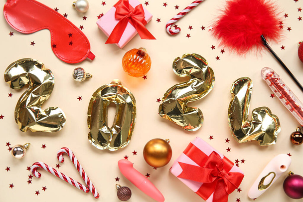 Σύνθεση με σχήμα 2024 από μπαλόνια, ερωτικά παιχνίδια και χριστουγεννιάτικες διακοσμήσεις σε φόντο χρώματος - Φωτογραφία, εικόνα