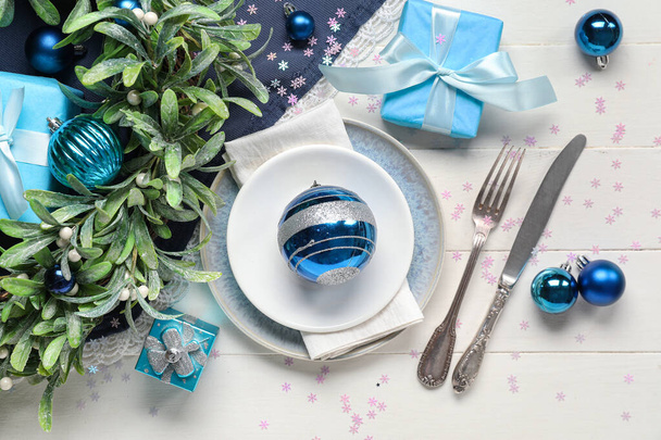 Ajuste de mesa festivo con cajas de regalo y decoraciones navideñas sobre fondo de madera blanca - Foto, imagen