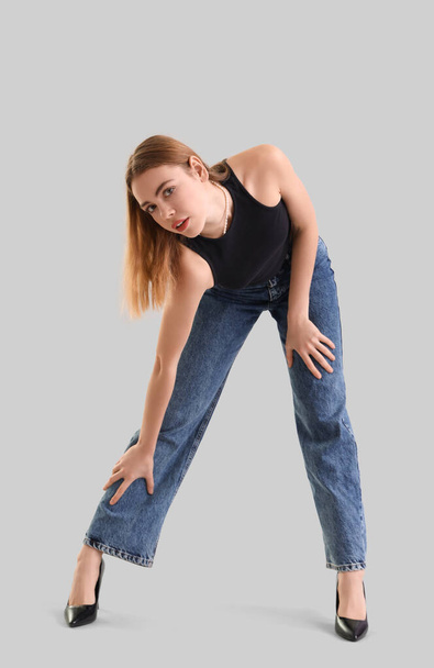 Młoda kobieta w ciemnoniebieskich dżinsach na jasnym tle - Zdjęcie, obraz