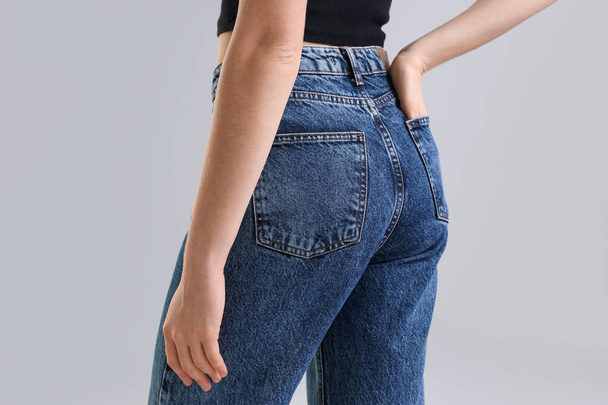 Giovane donna in jeans blu scuro su sfondo chiaro, vista posteriore - Foto, immagini