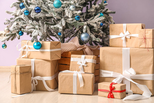 Many presents under beautiful Christmas tree near color wall, closeup - Photo, Image