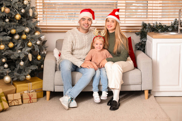 Κοριτσάκι με τους γονείς της να κάθονται σπίτι παραμονή Χριστουγέννων - Φωτογραφία, εικόνα