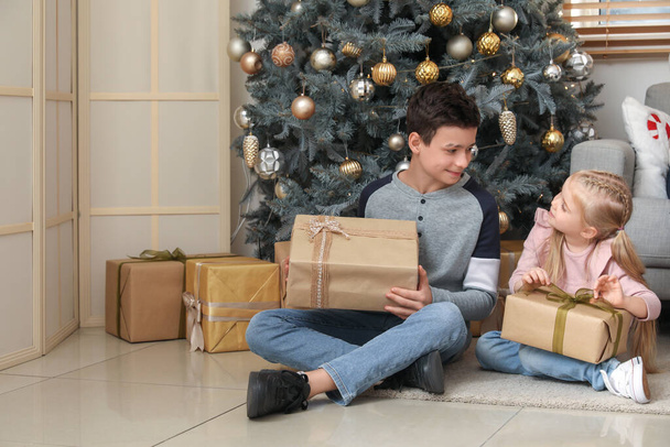 Małe dzieci z prezentami świątecznymi siedzą w domu - Zdjęcie, obraz