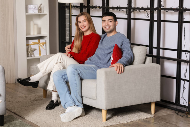 Junges Paar sitzt an Heiligabend zu Hause - Foto, Bild
