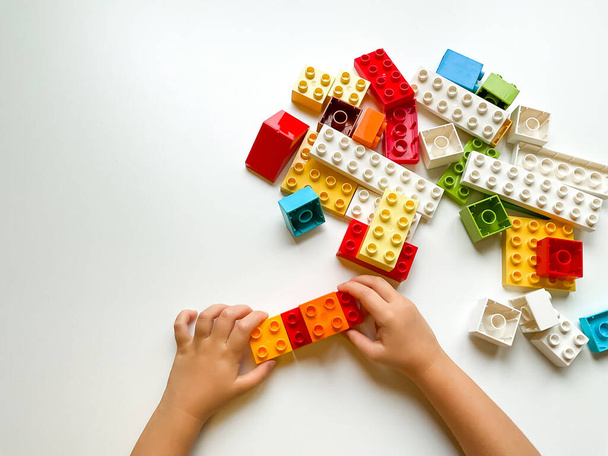 Bambino che gioca con blocchi colorati su sfondo bianco. Vista dall'alto. Foto di alta qualità - Foto, immagini