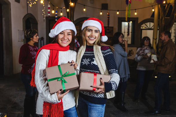 Posada Mexicana, mexikanische Mädchen oder Freundinnen mit Geschenken oder Geschenkschachteln, während sie Heiligabend in Mexiko Lateinamerika feiern - Foto, Bild