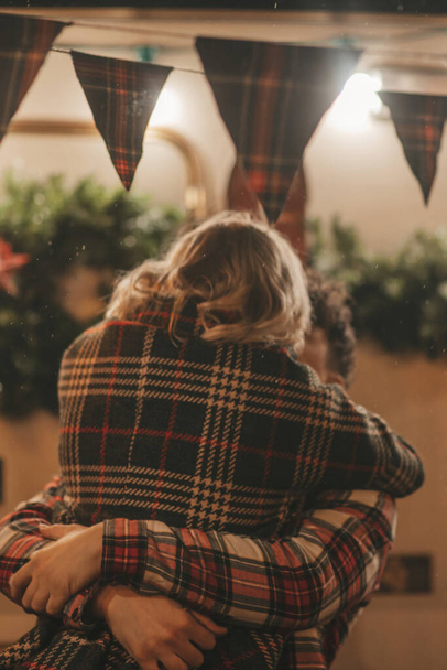 キャンパーパークでクリスマスと新年の冬の休暇シーズンを祝うハッピーカップル. 若いカップル休憩とリラクゼーション時間を一緒に過ごすXmasキャンピングカーのトレーラーの近くで抱擁とキス - 写真・画像