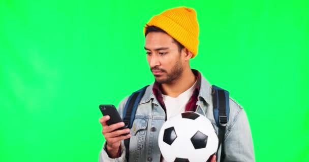 Молодий чоловік, зелений екран і телефон з футболом, смс і спілкування з читанням в студії. Студентський хлопець, смартфон та футбольний м'яч для спортивних азартних ігор, ставок та соціальних медіа. - Кадри, відео