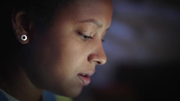 Lado close-up rosto bela jovem mulher negra americana olhando para a tela trabalhando com laptop indoor. Freelancer feminino digitando no computador à noite no quarto em casa. Conceito estudando gen z. - Filmagem, Vídeo