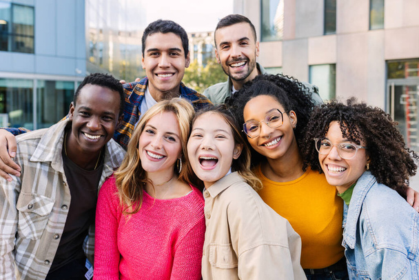 Portret van jonge groep uiteenlopende mensen die buiten naar de camera glimlachen. Gelukkige millennial college studenten genieten van tijd samen, sociale bijeenkomst en rondhangen in de stad straat. - Foto, afbeelding