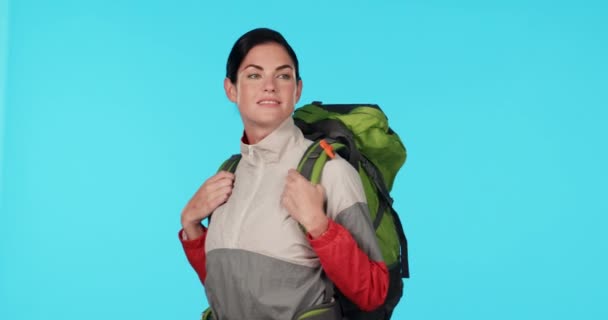 Travel, hiking with looking and woman in studio, adventure to watch nature and camping holiday. Trekking, sightseeing and hiker on journey, relax and view on vacation with backpack on blue background. - Footage, Video