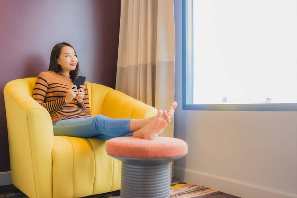 Портрет красива молода азіатка розслабляє посмішку в дії на дивані в інтер'єрі вітальні
 - Фото, зображення
