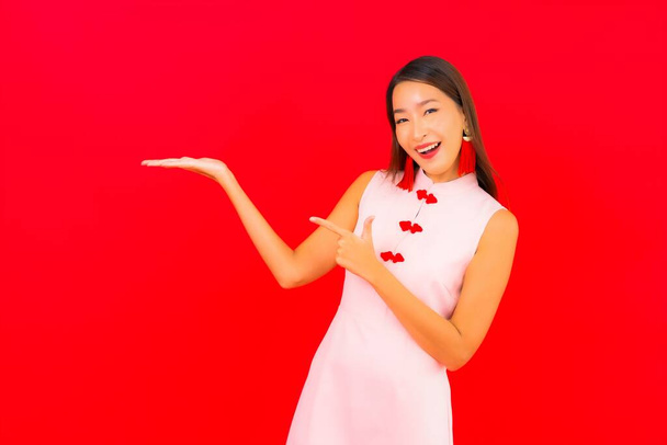 Porträt schöne junge asiatische Frau trägt chinesische Neujahrskleidung auf rotem Hintergrund - Foto, Bild