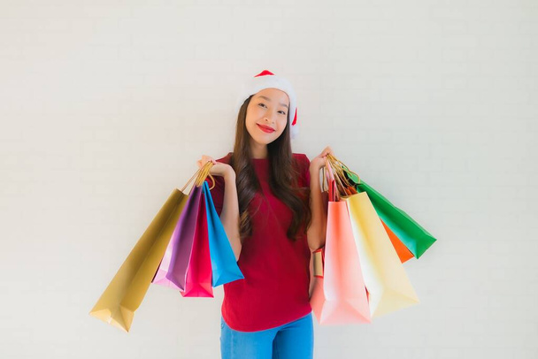 Retrato hermosa joven asiático mujeres usar navidad santa sombrero con bolsa de compras de grandes almacenes
 - Foto, imagen