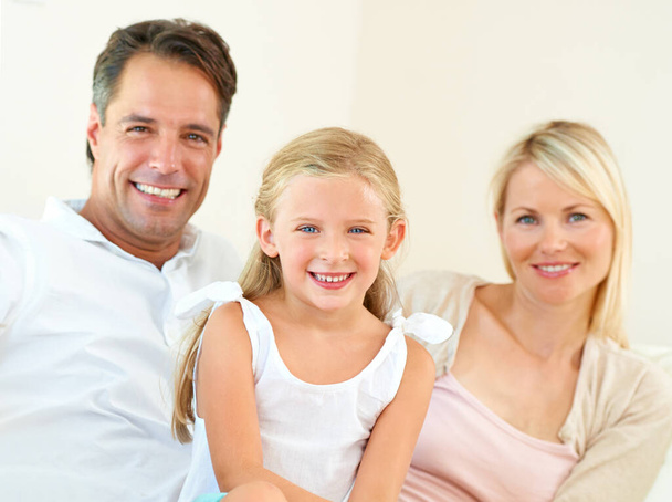 Family, portrait and happy on sofa with relax, peace and love for bonding and relationship in living room. Parents, girl kid or face and smile on couch of lounge for care, break and enjoyment in home. - Photo, Image