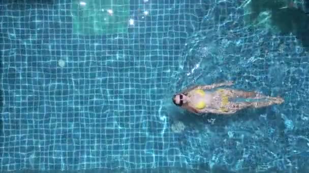 Top kilátás fiatal kaukázusi nő úszik a háton a medencében lassított felvételen. - Felvétel, videó