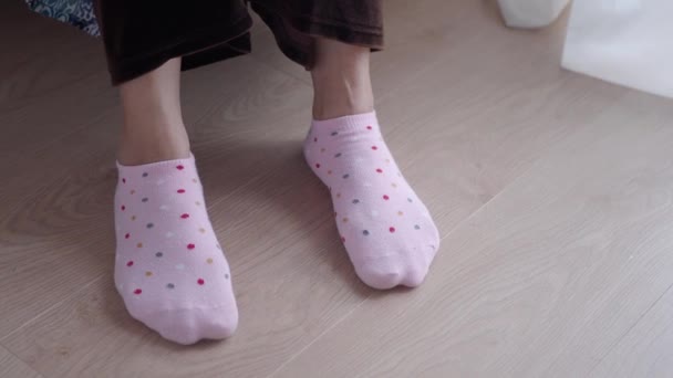 Frauen ziehen rosafarbene Socken an, die auf dem Sofa sitzen . - Filmmaterial, Video