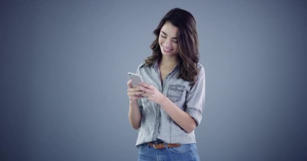 Happy woman, phone and texting for communication in studio with social media mock up on gray background. Person, smile and face for looking at screen, email or message on mobile app, web or internet. - Footage, Video