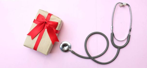 медичний стетоскоп з подарунковою коробкою ізольовано на рожевому пастельному тлі. концепція Різдво і Новий рік.горизонтальна фотографія - Фото, зображення