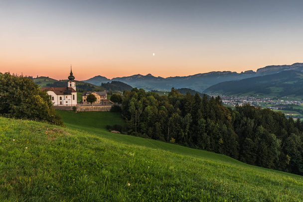 Church in the Appenzell Alps with view to the Alpstein mountains with Hoher Kasten and the village of Appenzell at dusk, Schlatt-Haslen, Canton Appenzell Innerrhoden, Switzerland - Photo, Image