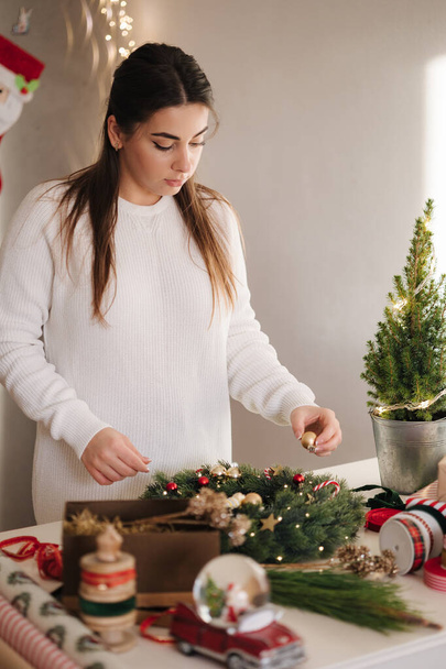 Мама і дочка роблять різдвяний вінок з використанням свіжих гілок сосни та святкових прикрас. Різдвяний настрій. Високоякісна фотографія - Фото, зображення