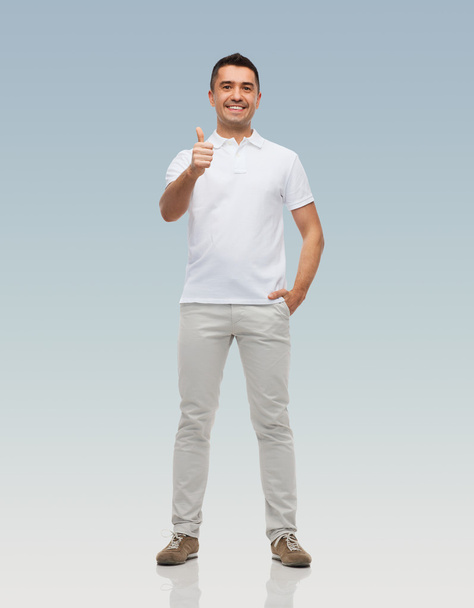 smiling man showing thumbs up over gray background - Foto, Imagen