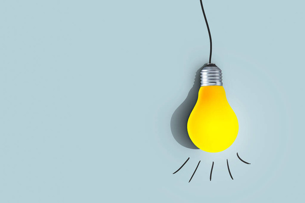 Creative yellow light bulb hangs and glows on a blue background. Think differently, concept. Successful project. Learning and Thoughts - Photo, Image