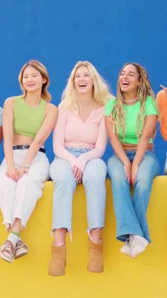 Відео повільного руху багатоетнічних друзів жінок, що сидять на барвистій міській стіні, махаючи - Кадри, відео