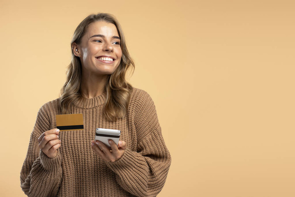Muotokuva kaunis hymyilevä nainen tilalla matkapuhelin, luottokortti ostoksia verkossa myynti eristetty taustalla, kopioi tilaa. Internet-kauppa, sähköisen rahan käsite  - Valokuva, kuva