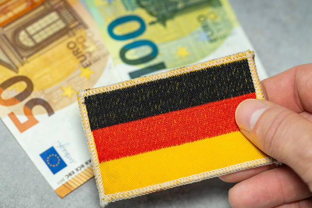 Λεφτά σε ευρώ, χρηματοοικονομική κατάσταση της Γερμανίας, γερμανική σημαία με φόντο τα χαρτονομίσματα των 50 και των 100 ευρώ - Φωτογραφία, εικόνα