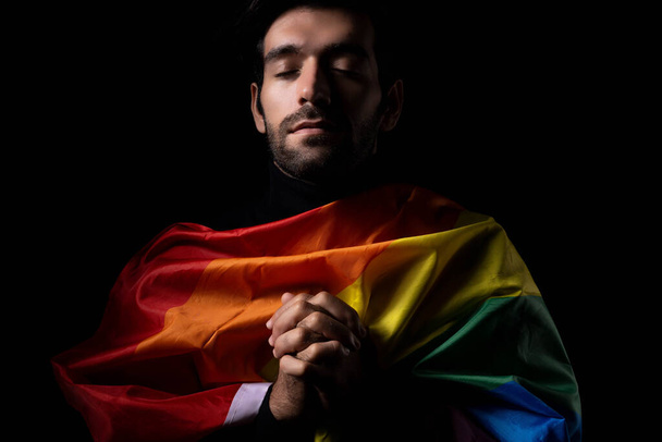 LGBTQ Gay muž modlí za rovná práva Duhová vlajka homosexuální hrdost vlajka On je Gay Pýcha a hrdý Muž modlí za rovnost zavřít oči kryt duha vlajka s černým pozadím LGBTQIAN + Pýcha Měsíc koncept - Fotografie, Obrázek