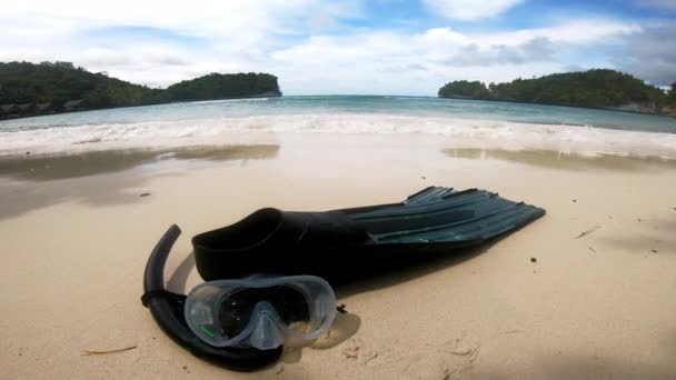 Snorkel, equipment and flipper on beach with waves for fun, adventure or exploring on tropical holiday. Cool, summer and ocean breeze with goggles for diving in Indonesia on trip, travel or vacation. - Séquence, vidéo